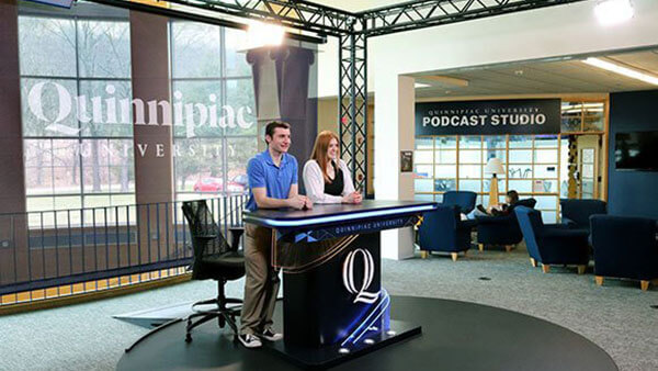 Students stand at a desk in the School of Communications open-air studio