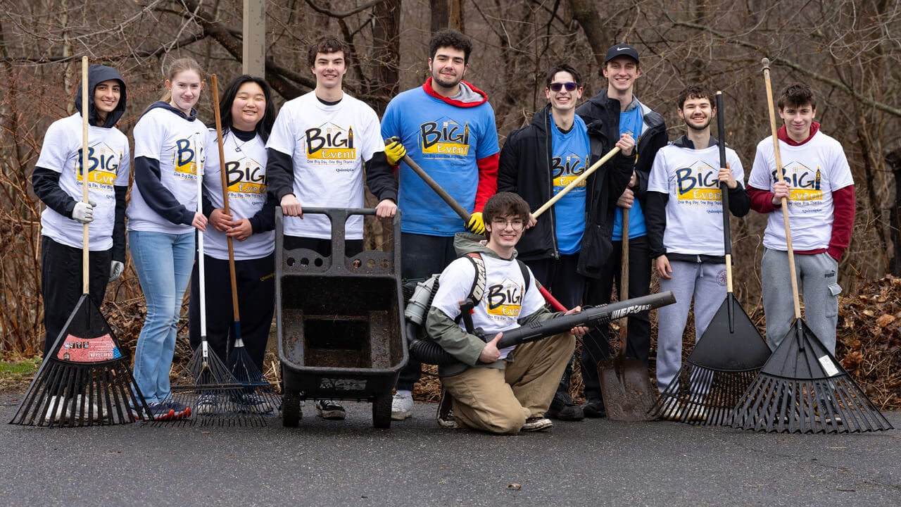 People pose for a group photo holding tools