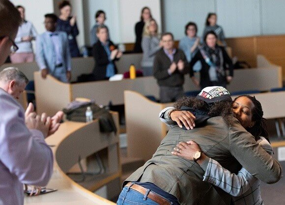Bettina Love hugs a woman as a crowd of people stand and clap.