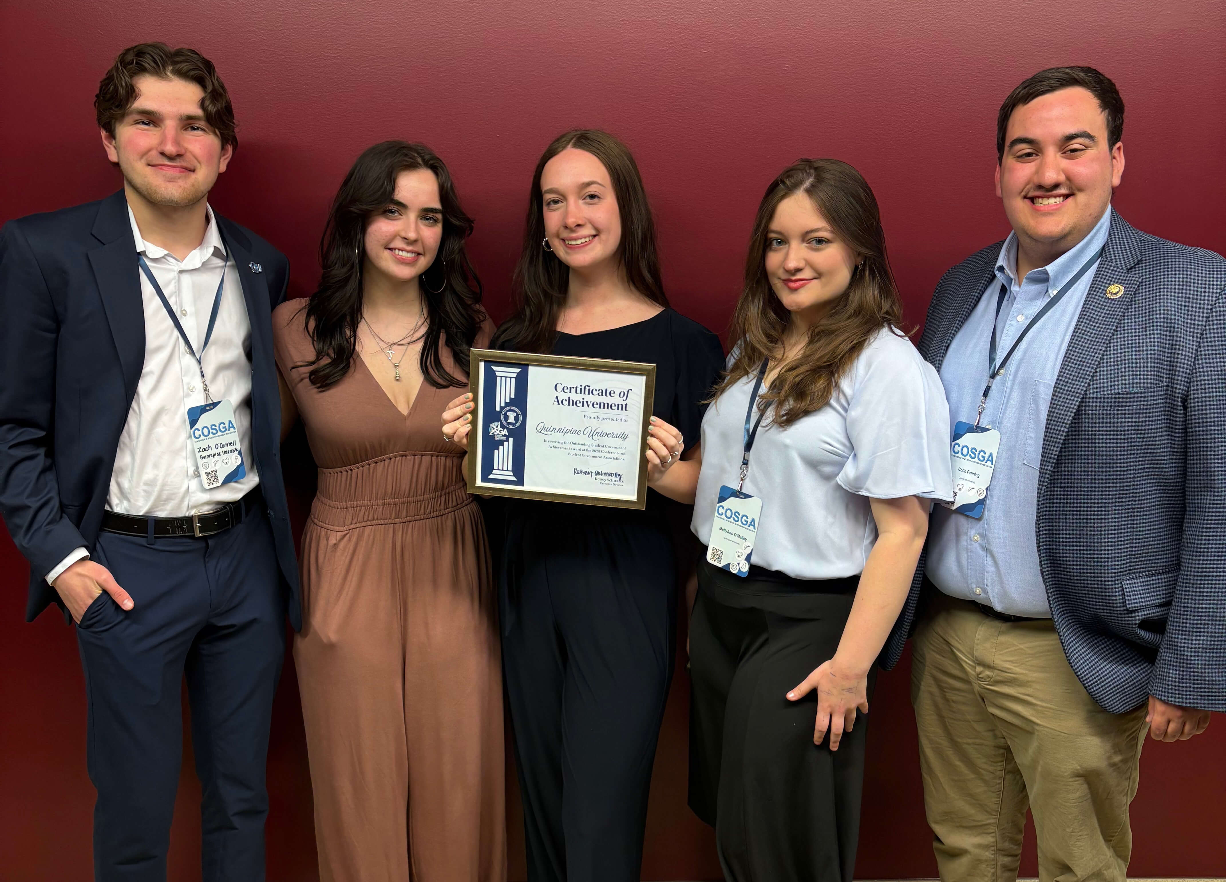 Five students pose for a photo with an award plaque