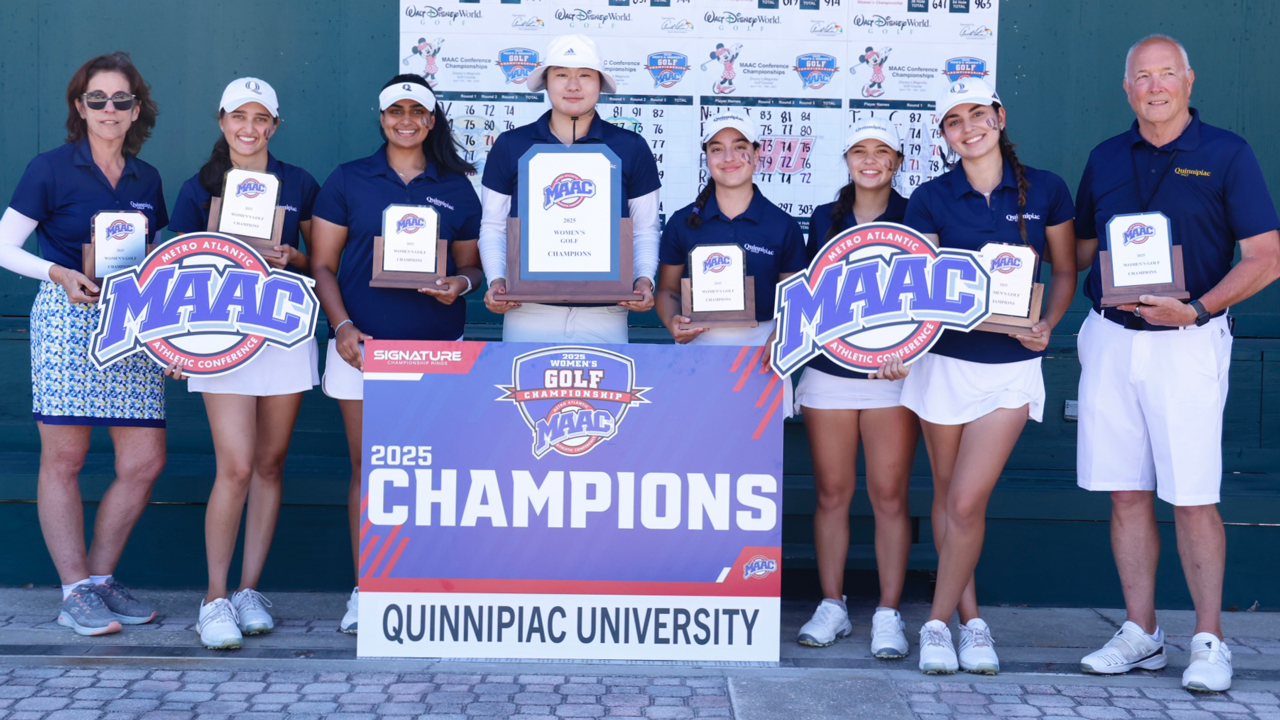 Women's golf team players and coaches hold MAAC trophies and Championships signs and smile for a photo