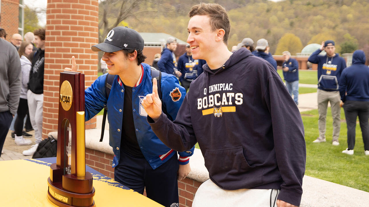 Students posing in front of the 2023 NCAA National Championship trophy