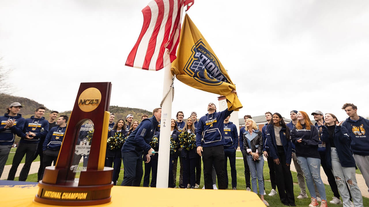 Men's ice hockey team helping raise the national championship flag