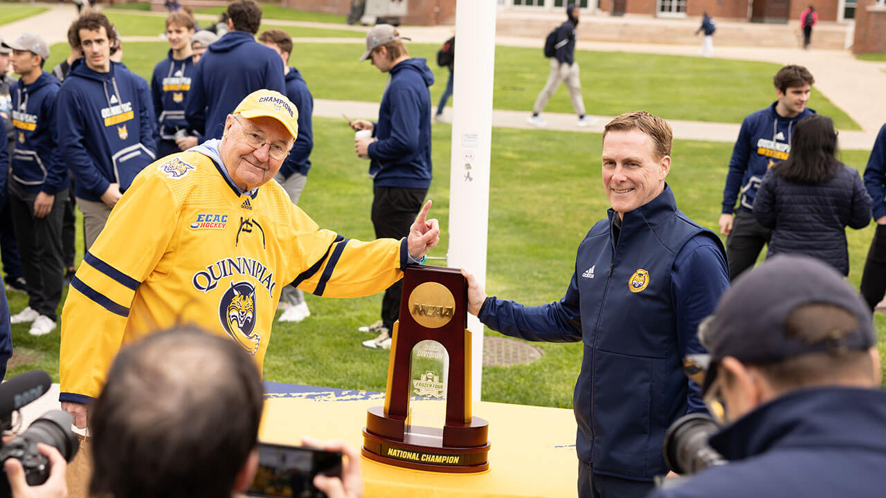 Rand Pecknold posing in front of the NCAA National Championship trophy