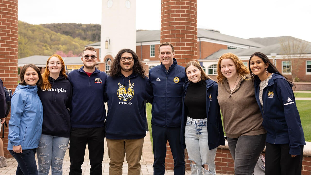 Students pose with mens ice hockey coach Rand Pecknold