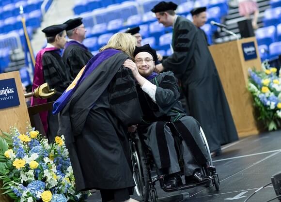 A student and administrator embrace during the ceremony.