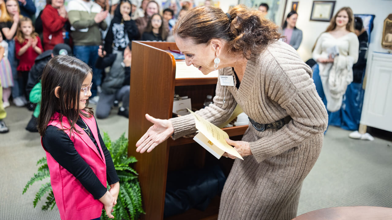 Dean of the Quinnipiac University School of Education Anne M. Dichele, right, presents 8-year-old April Peris, a Side by Side Charter School student, with a certificate during the Kaleidoscope of Creativity event.