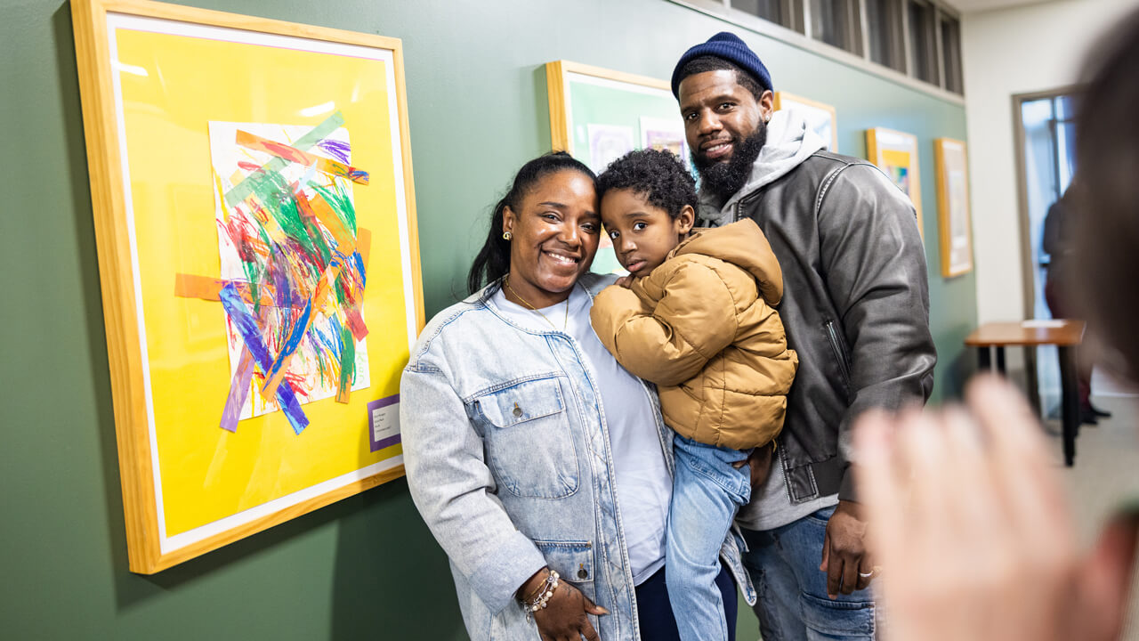 Four-year-old Kion Morgan, a pre-school student at Alice Peck Learning Center, and his parents Kierra Scott-Morgan and Norris Morgan of Hamden pose for a photo in front Kion’s artwork “Unlimited color” during the Kaleidoscope of Creativity event.