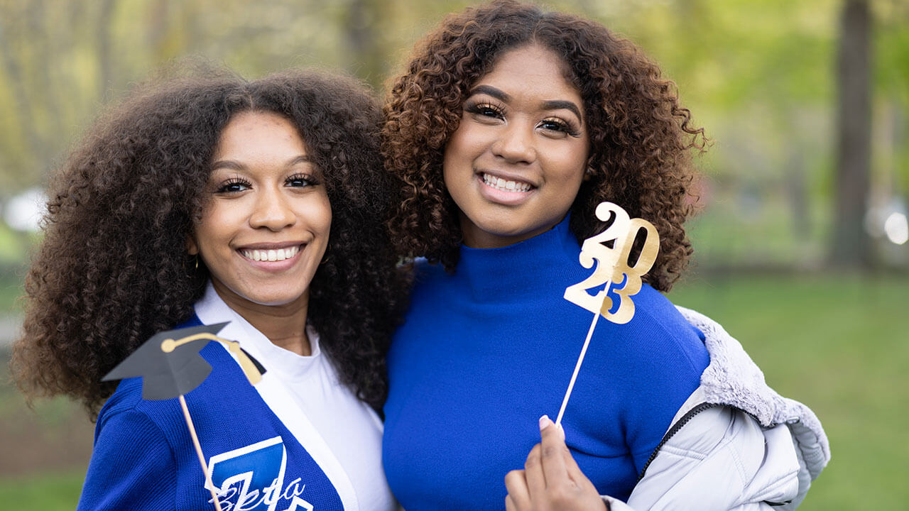 Two students smile for a photo together during their graduation toast
