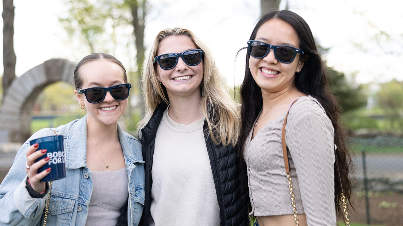 Students pose for a picture in their alumni branded sunglasses