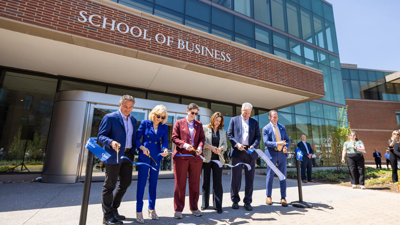 A group of Quinnipiac leaders cut a ceremonial ribbon in front of the new School of Business