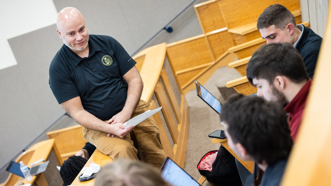 Students receiving guidance from faculty while working on laptops.