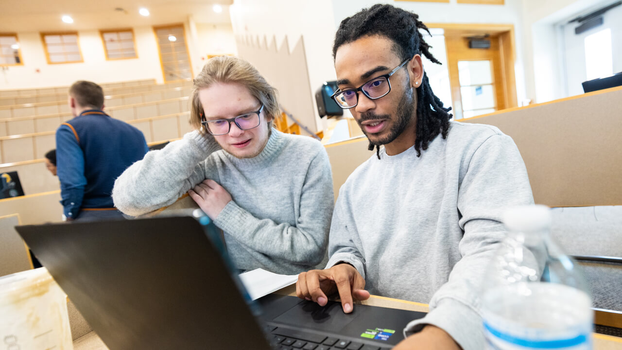 Students collaborating while working on laptops.
