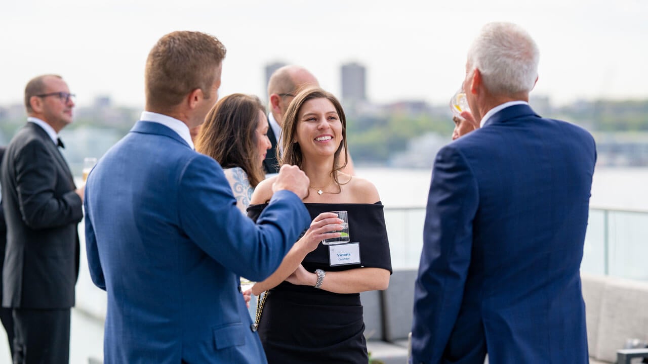 People discuss among each other with the Manhattan skyline in the background.