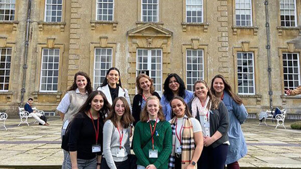 A group of students stand together outside a building at the University of Oxford in the United Kingdom