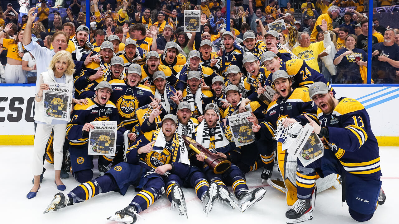 Judy Olian poses with the National Championship men's ice hockey team