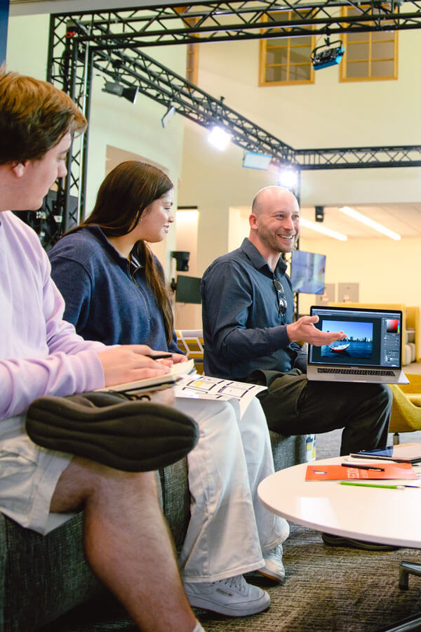 Students discuss photoshop techniques with a visual design professor.