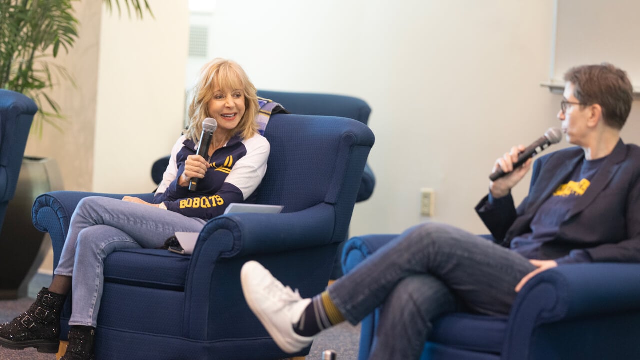 Judy Olian holds a microphone