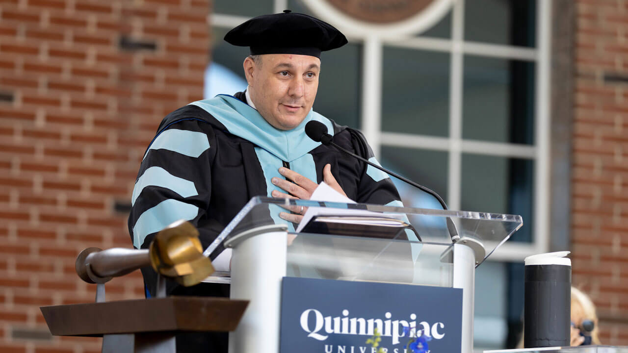 Joseph DiBacco speaks infront of podium during Commencement