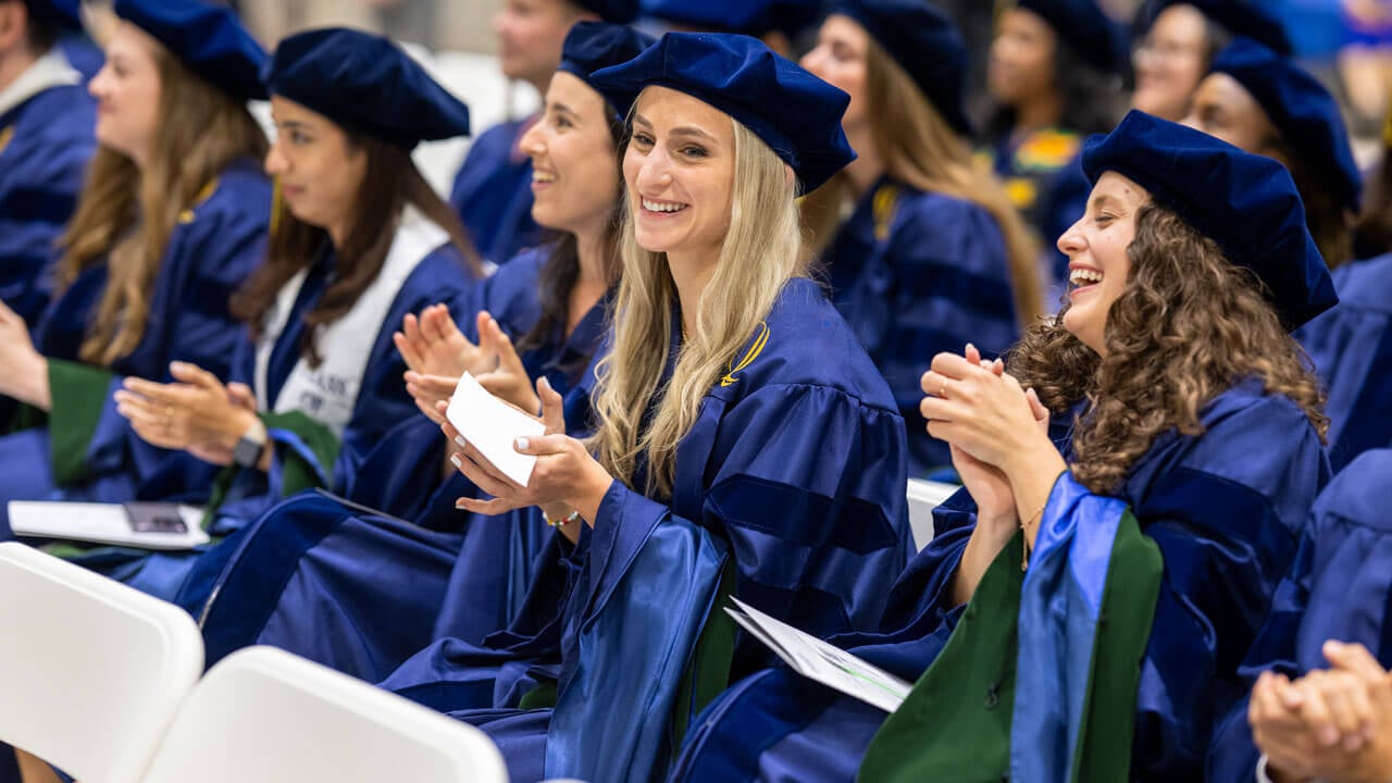 Graduates clap in their seats during the commencement ceremony.