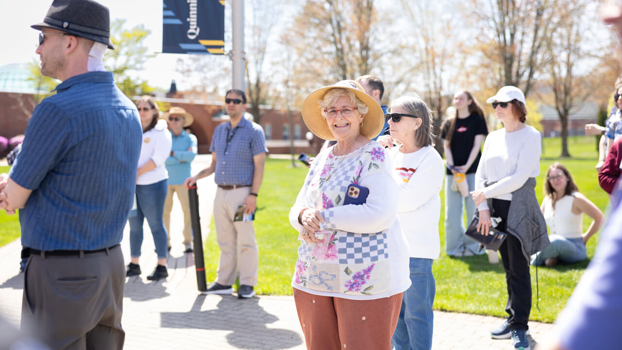 A community member in a broad sun hat smiles during the Inaugural Tree Walk Ceremony
