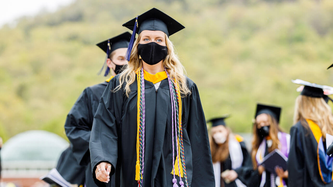 Girl in cap and gown while standing at commencement