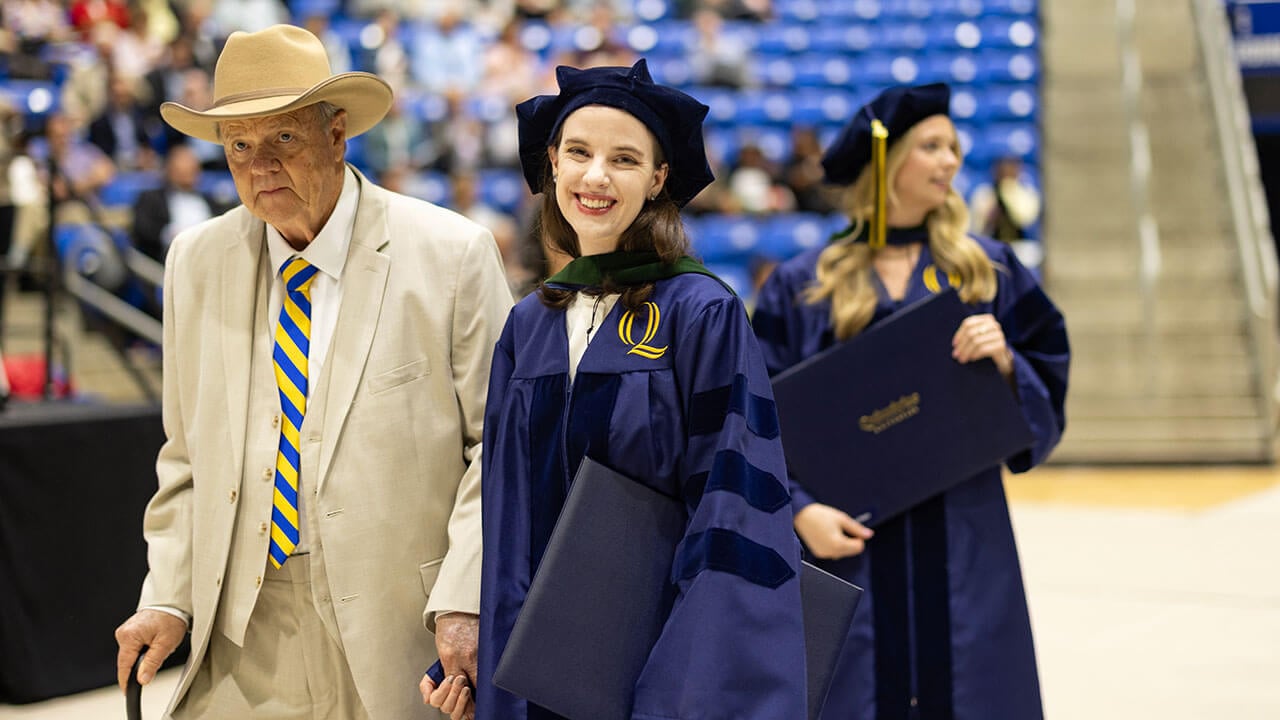 A graduate walking off stage with a family member