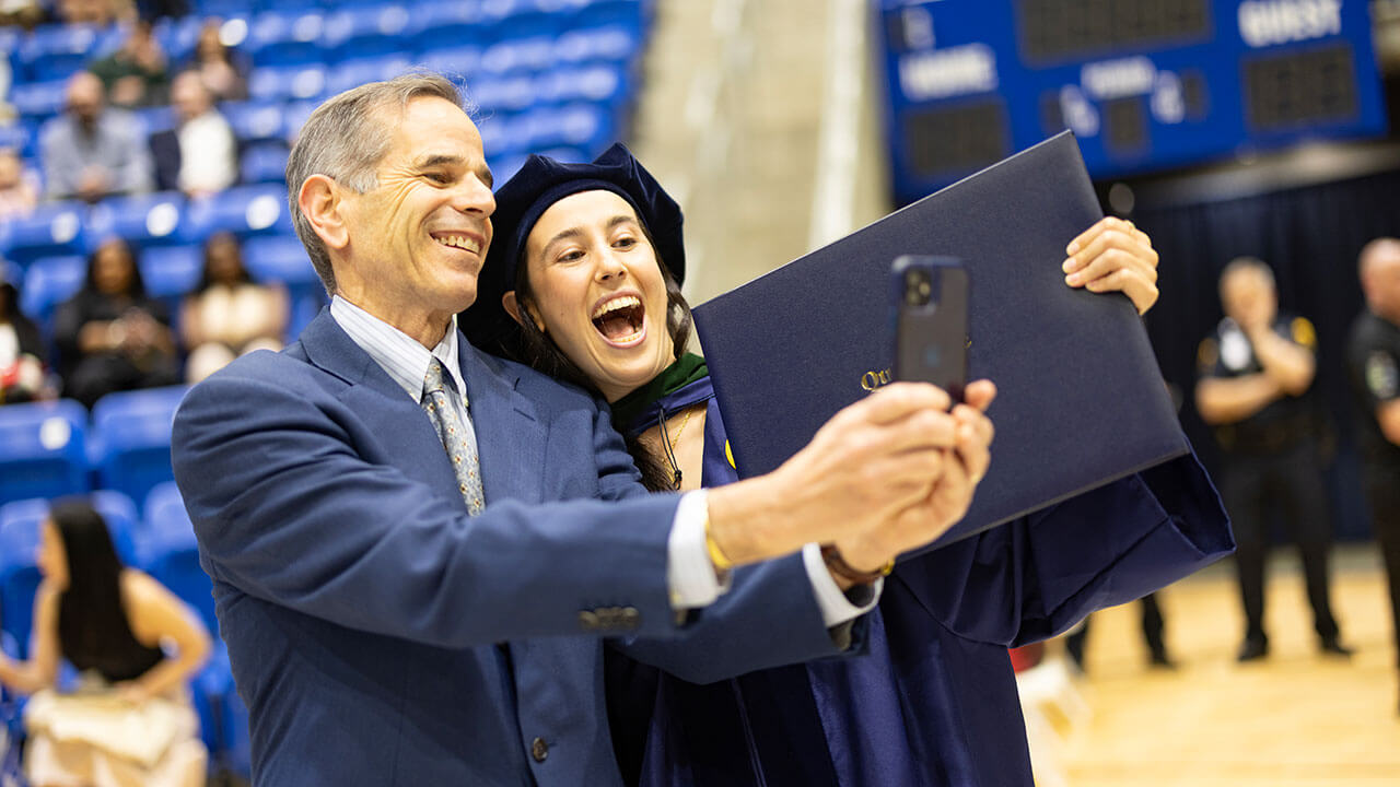 A grad taking a selfie after receiving their diploma