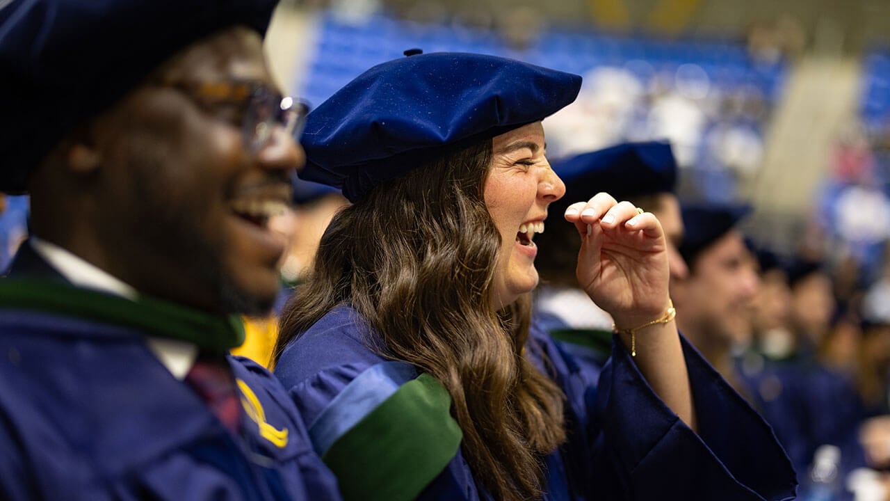 A graduate in the crowd laughing