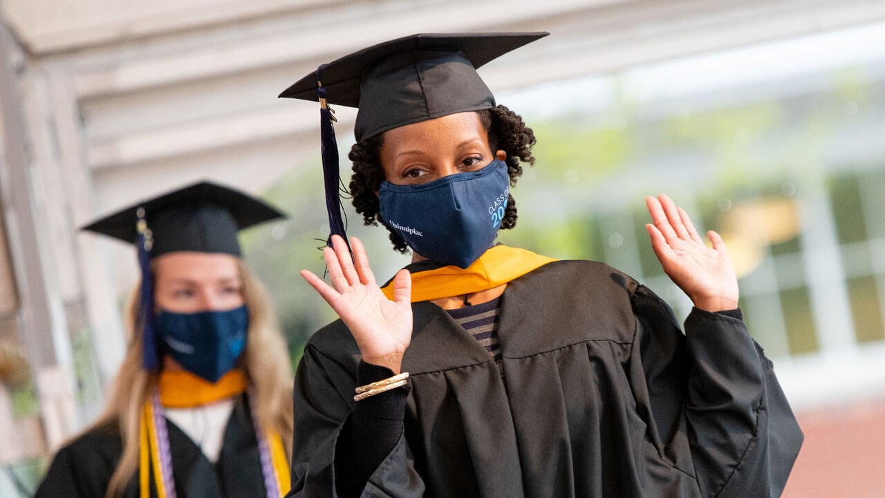 A graduate raises her arms in celebration