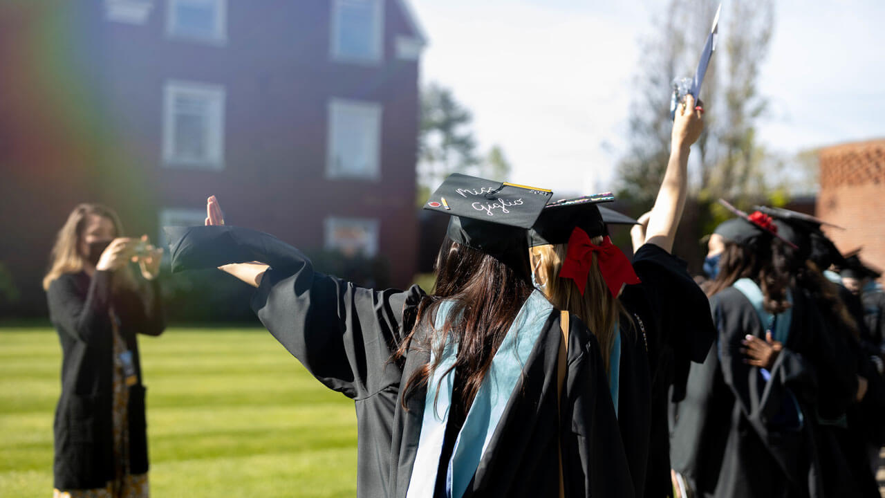 Students taking picture together and throwing arms up in the air with backs facing camera