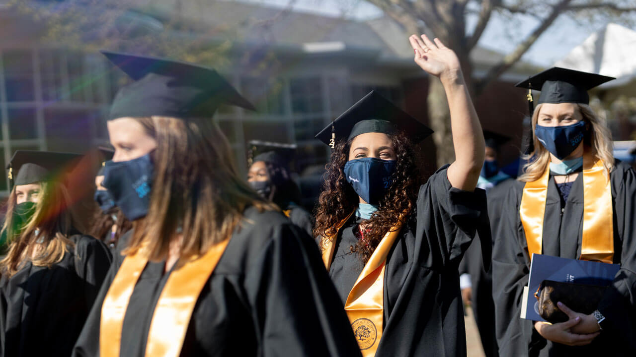 Girl waving at camera while standing in line