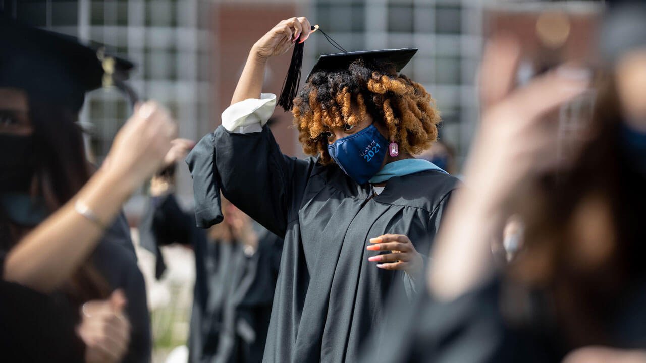 A graduate moves her tassel to the other side of her Commencement cap