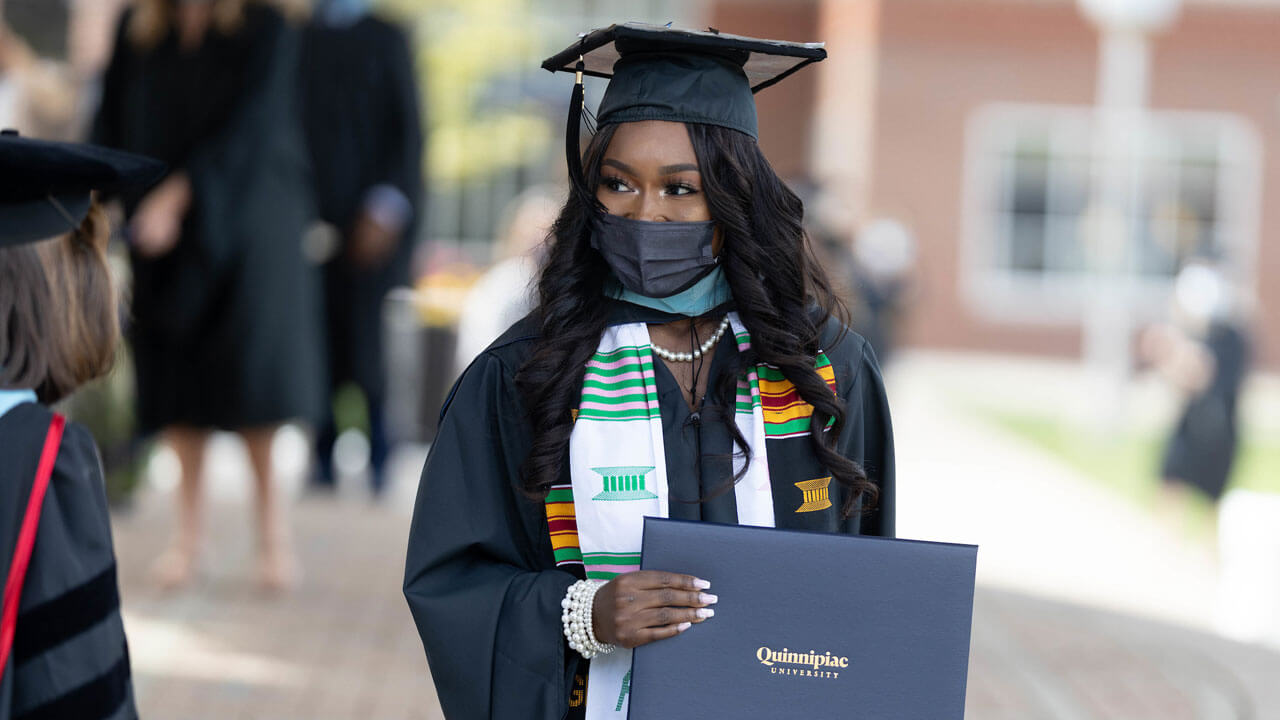 A graduate smiles at a faculty member as she crosses the Commencement stage