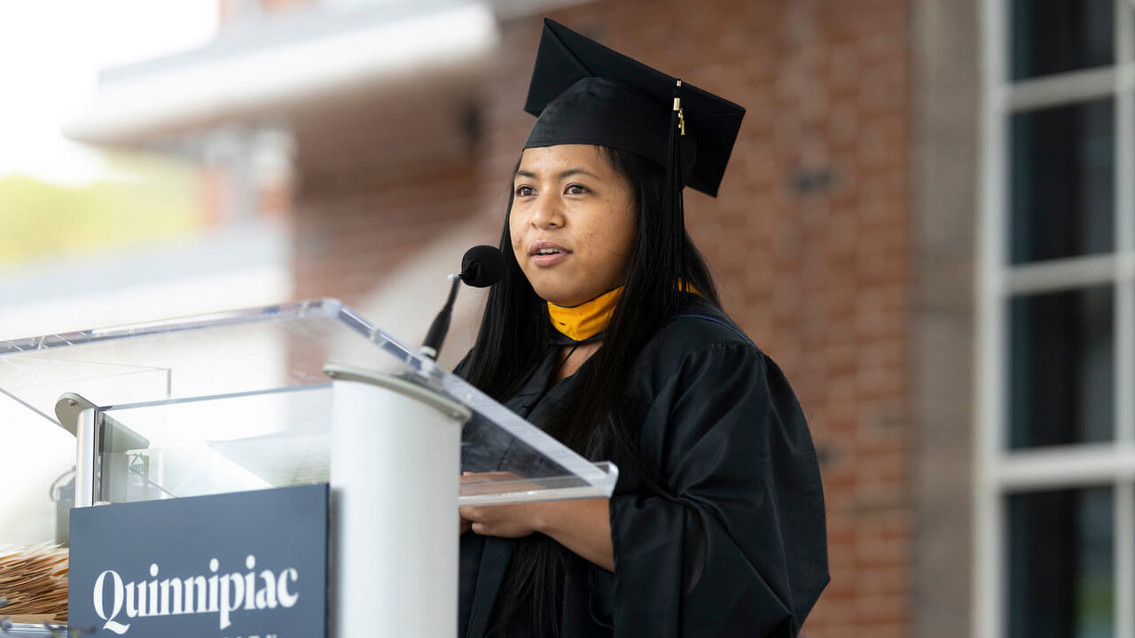 Kristelle Jasmine Cayong Caslang speaking on podium infront of graduate class
