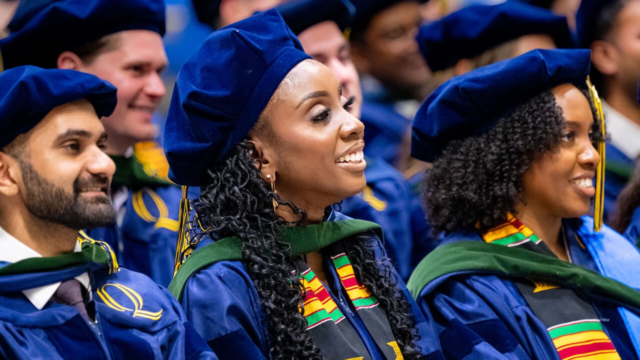 Graduates smile while seated