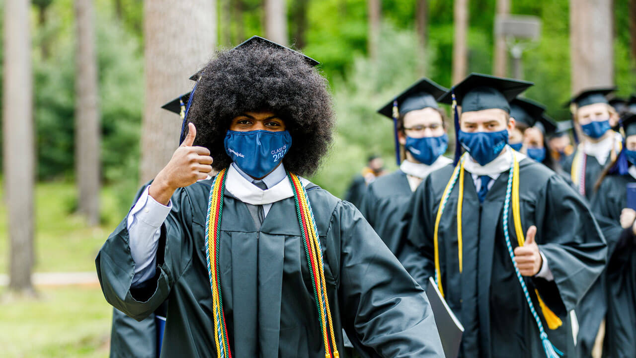 A graduate gives a celebratory thumbs up