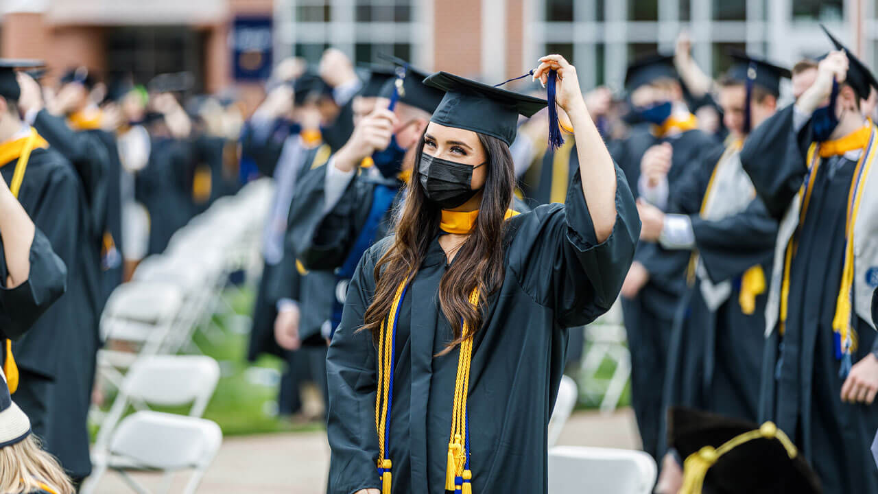 Dozens of graduates move their tassels to the other side of their caps