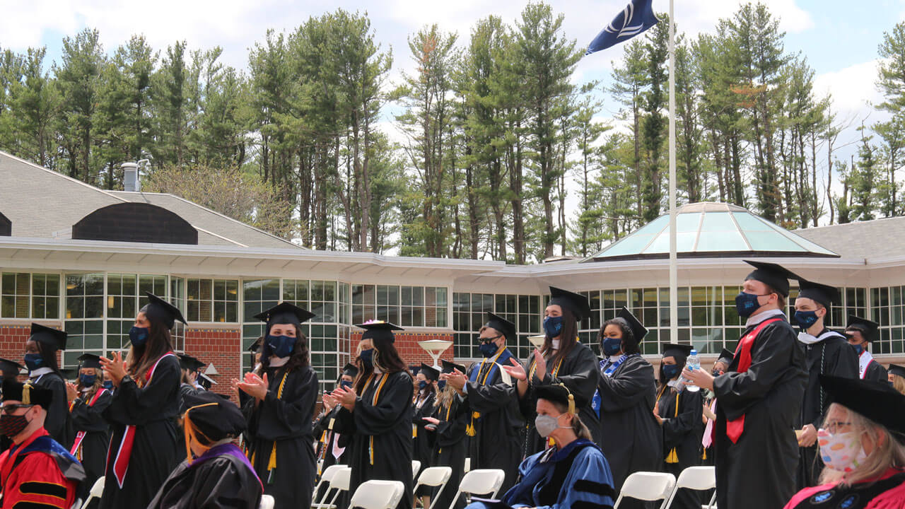 Students clapping and standing by chairs infront of student center
