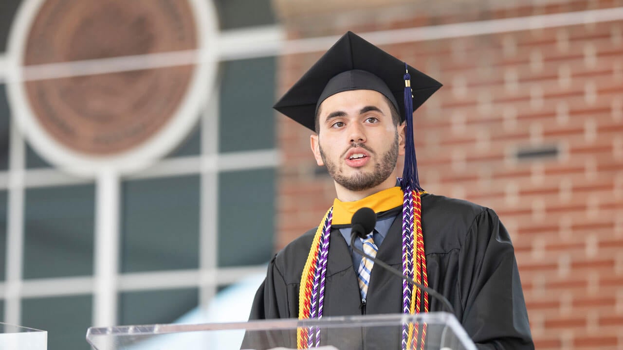 Michael Giannone speaks at a podium on the library steps