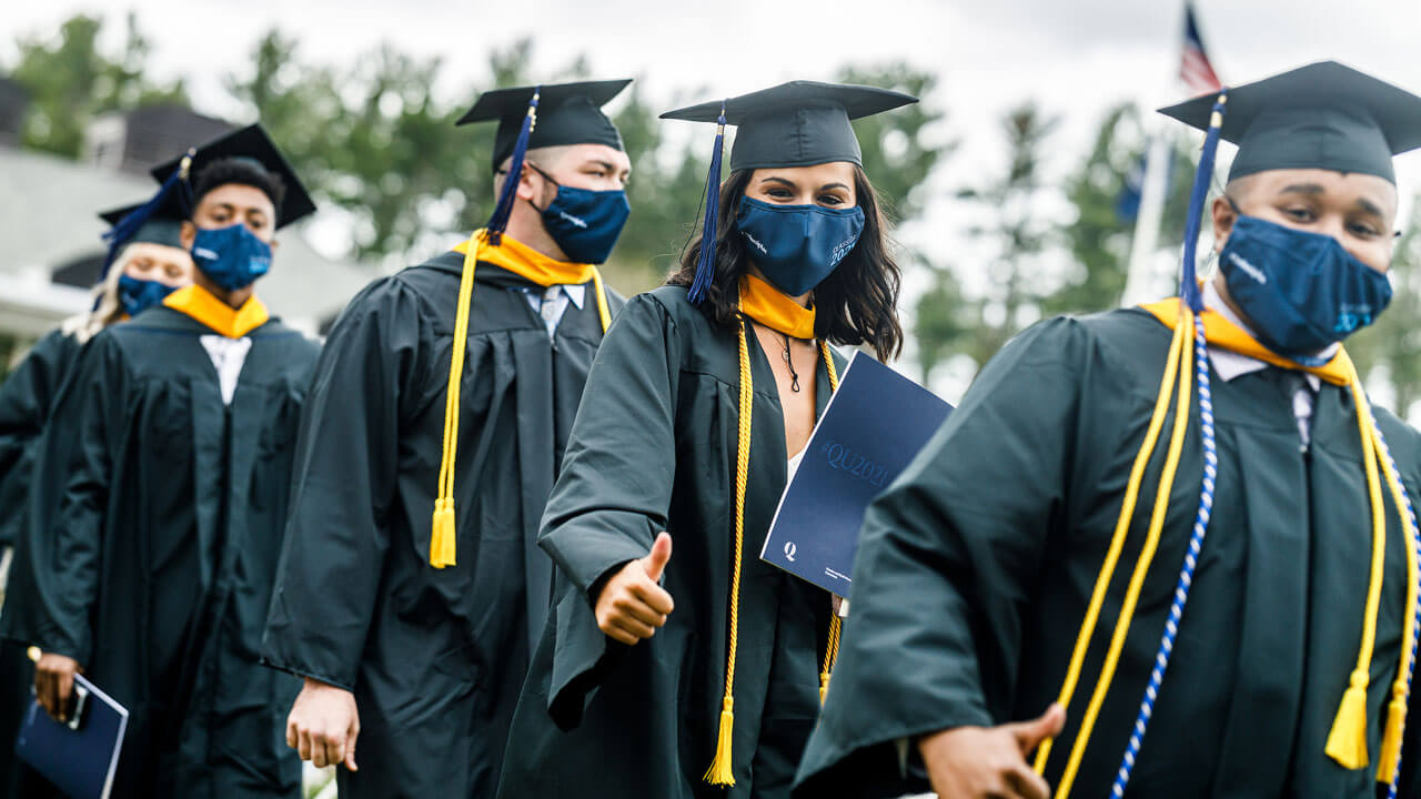 Several graduates walk in a line after receiving their diplomas