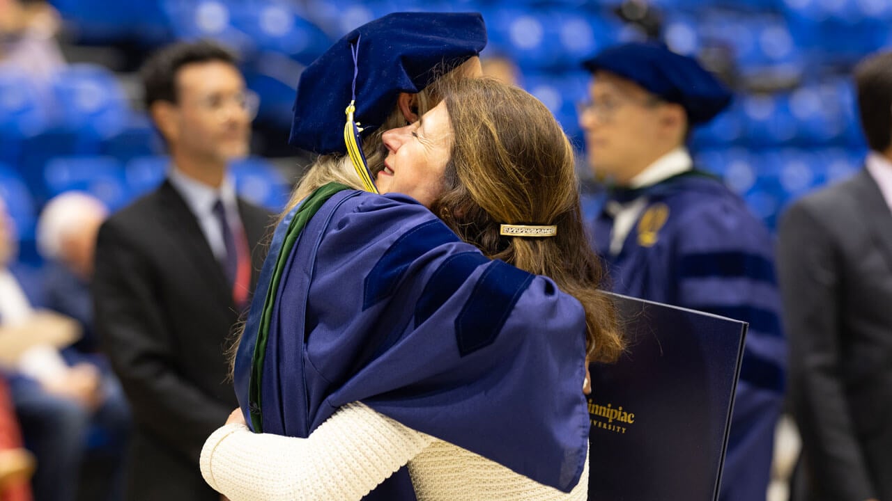 A graduate hugs a loved one.