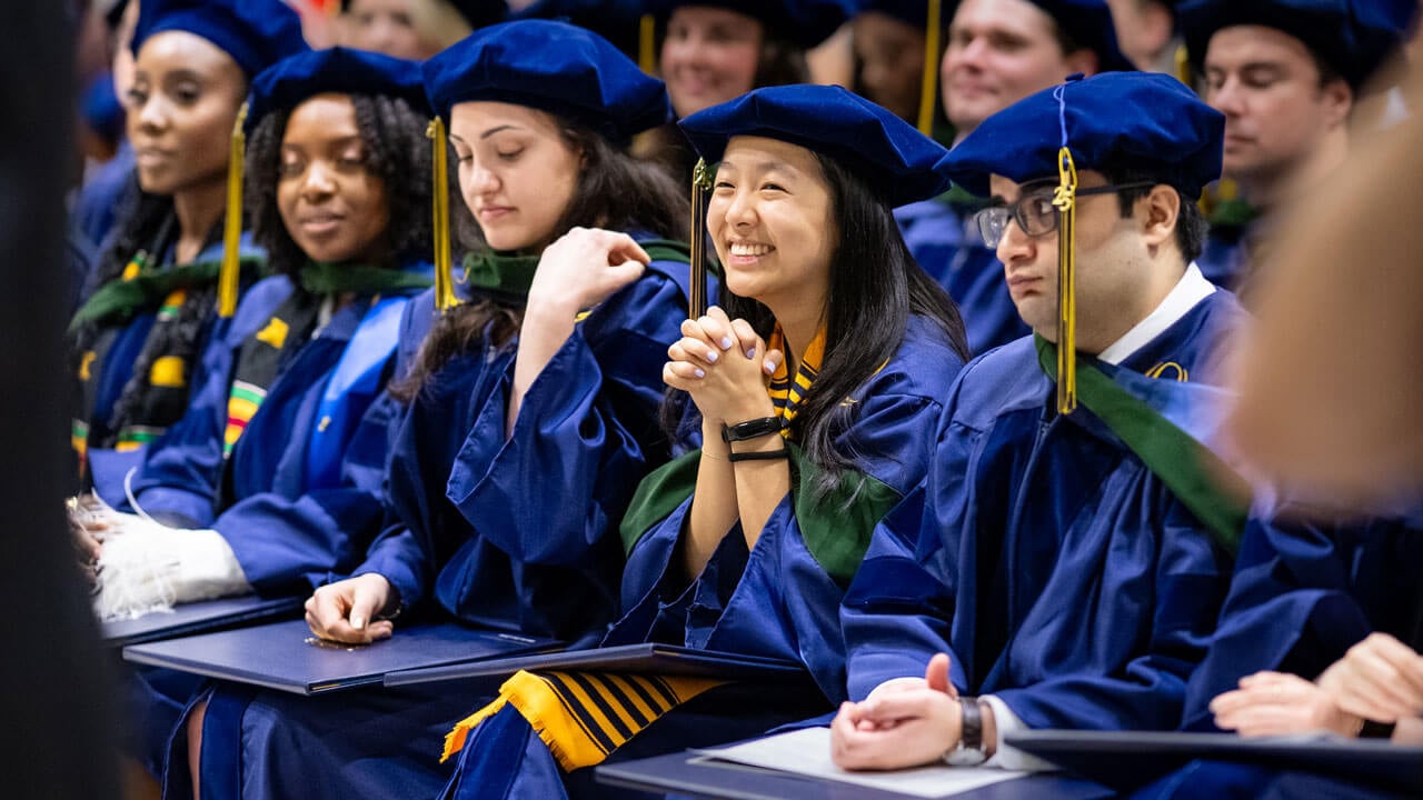 Graduate stares in excitement in the crowd.