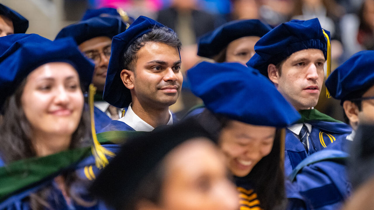 Graduates smile in crowd during ceremony.