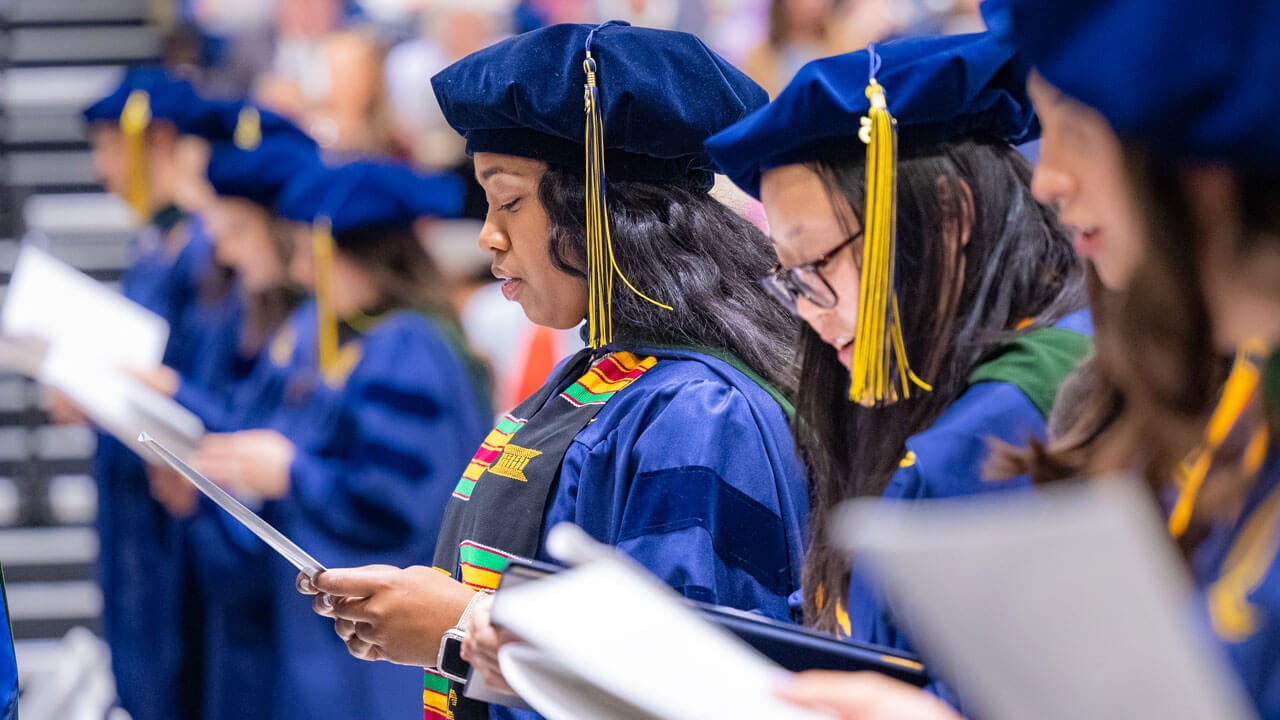 Graduate reads from their program in the crowd.