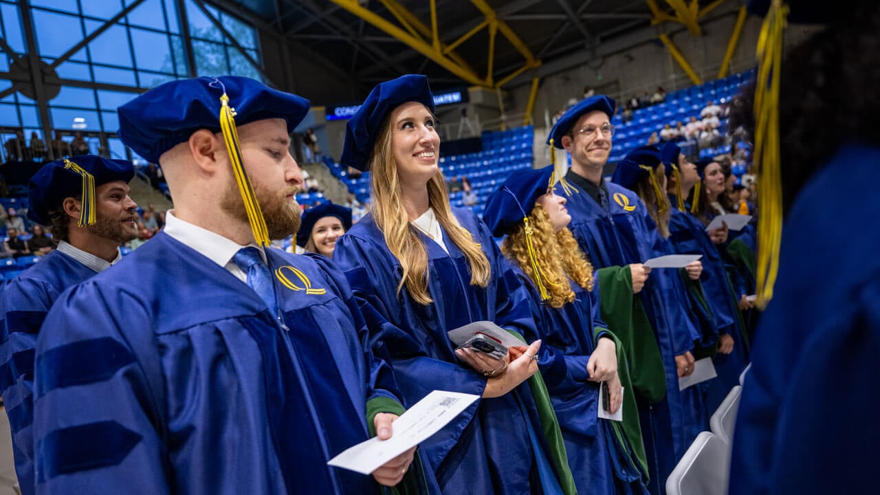 Graduate stands while smiling
