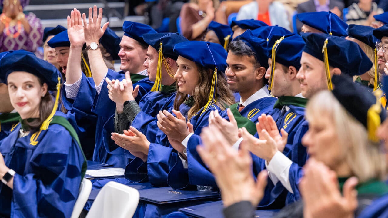Graduates clap during commencement ceremony.