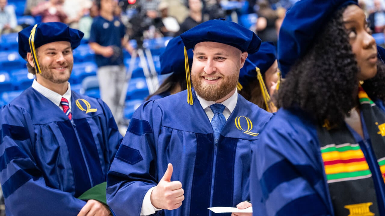Graduate gives thumbs up while walking