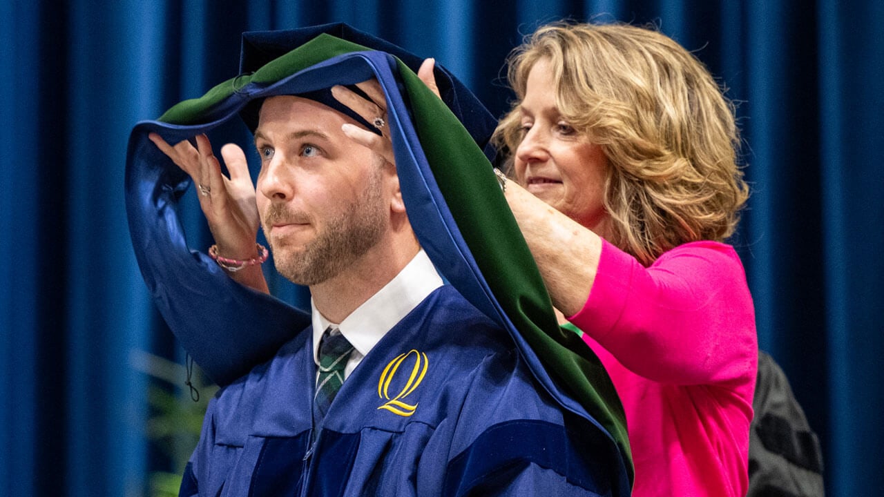 A loved one places a hood over a graduate.