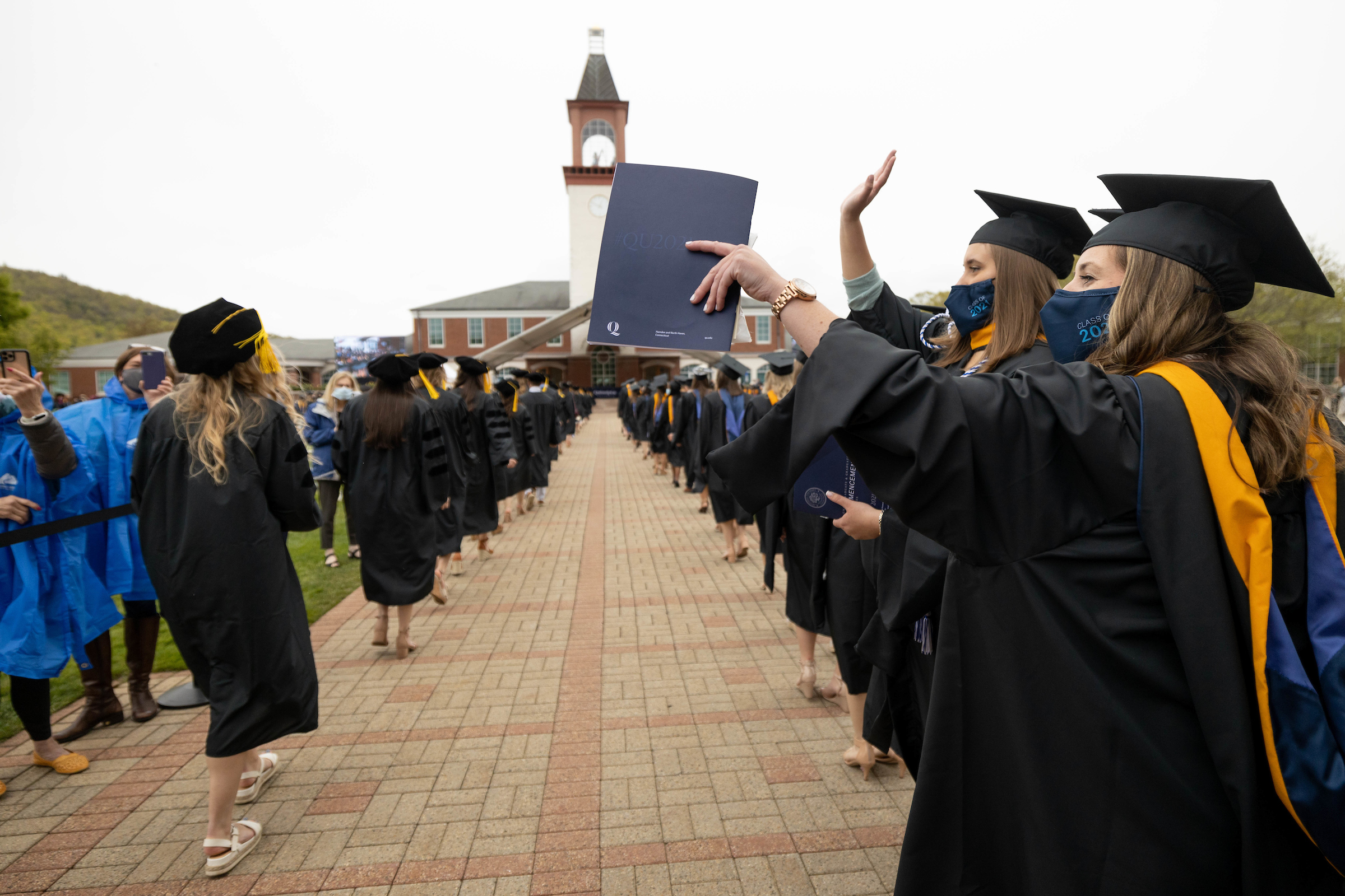 Students walking down the aisle waving at parents